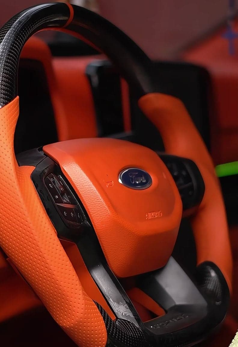 Custom steering wheel in orange perforated leather and carbon fibre