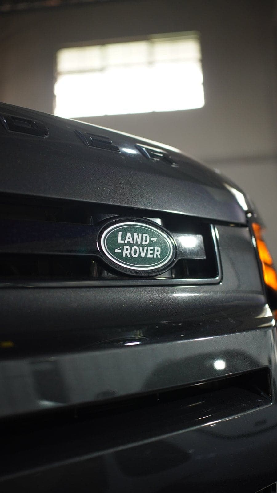 Land Rover badge on the grille of a dark grey Defender
