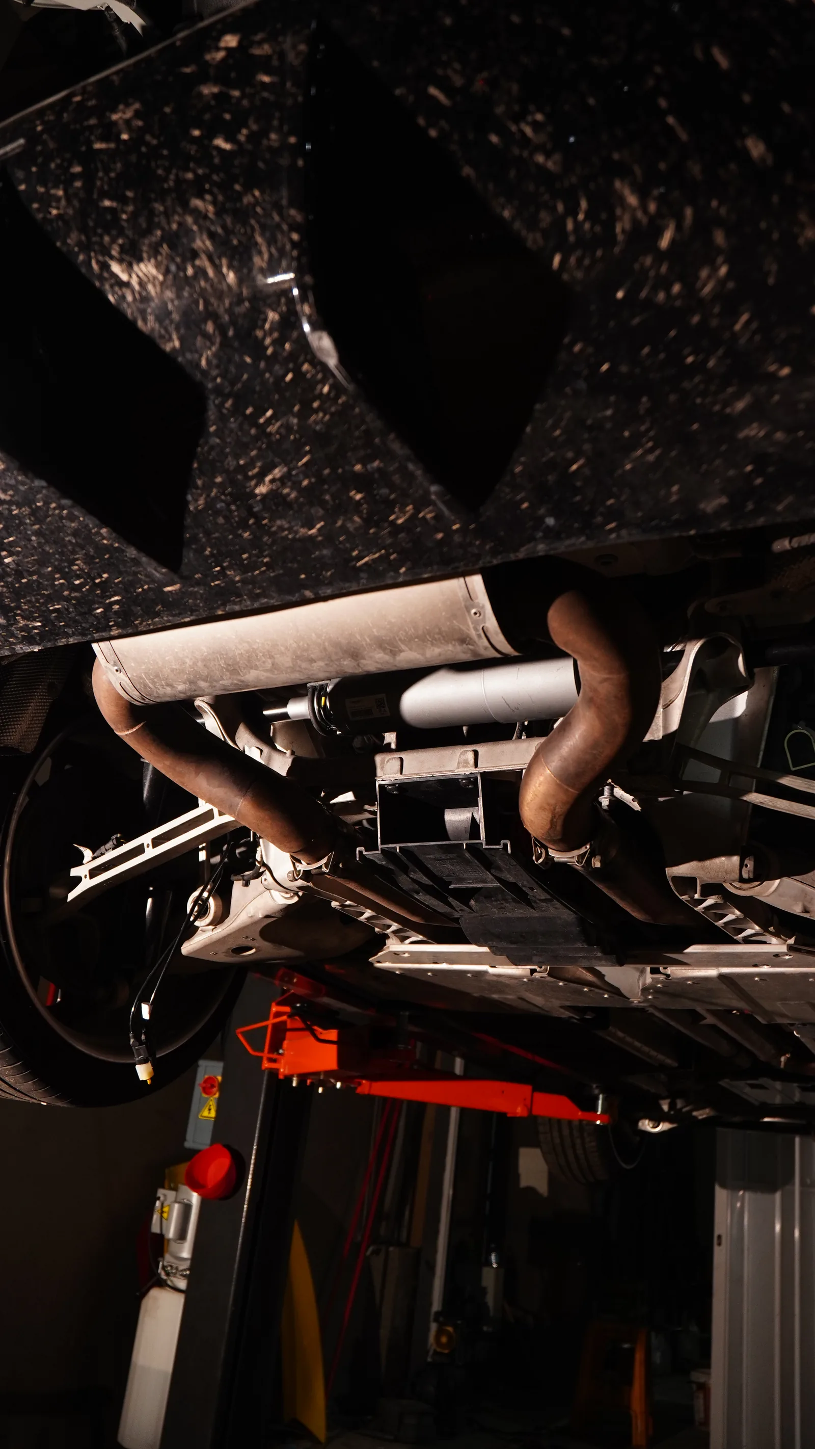 Aston Martin DBX on the lift seen from underneath, showing the forged carbon diffuser, exhaust and rear suspension
