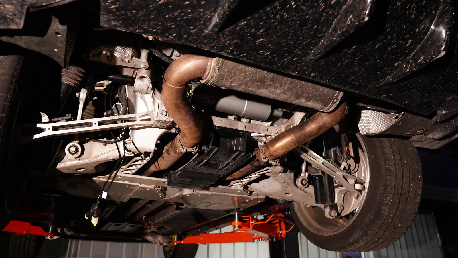 Underside of the Aston Martin DBX on the lift with the exhaust, rear subframe and suspension in view