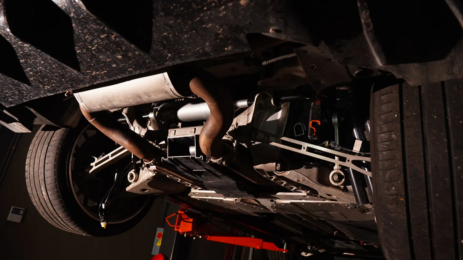 Aston Martin DBX rear underbody on the lift, with both rear wheels, exhaust and suspension arms