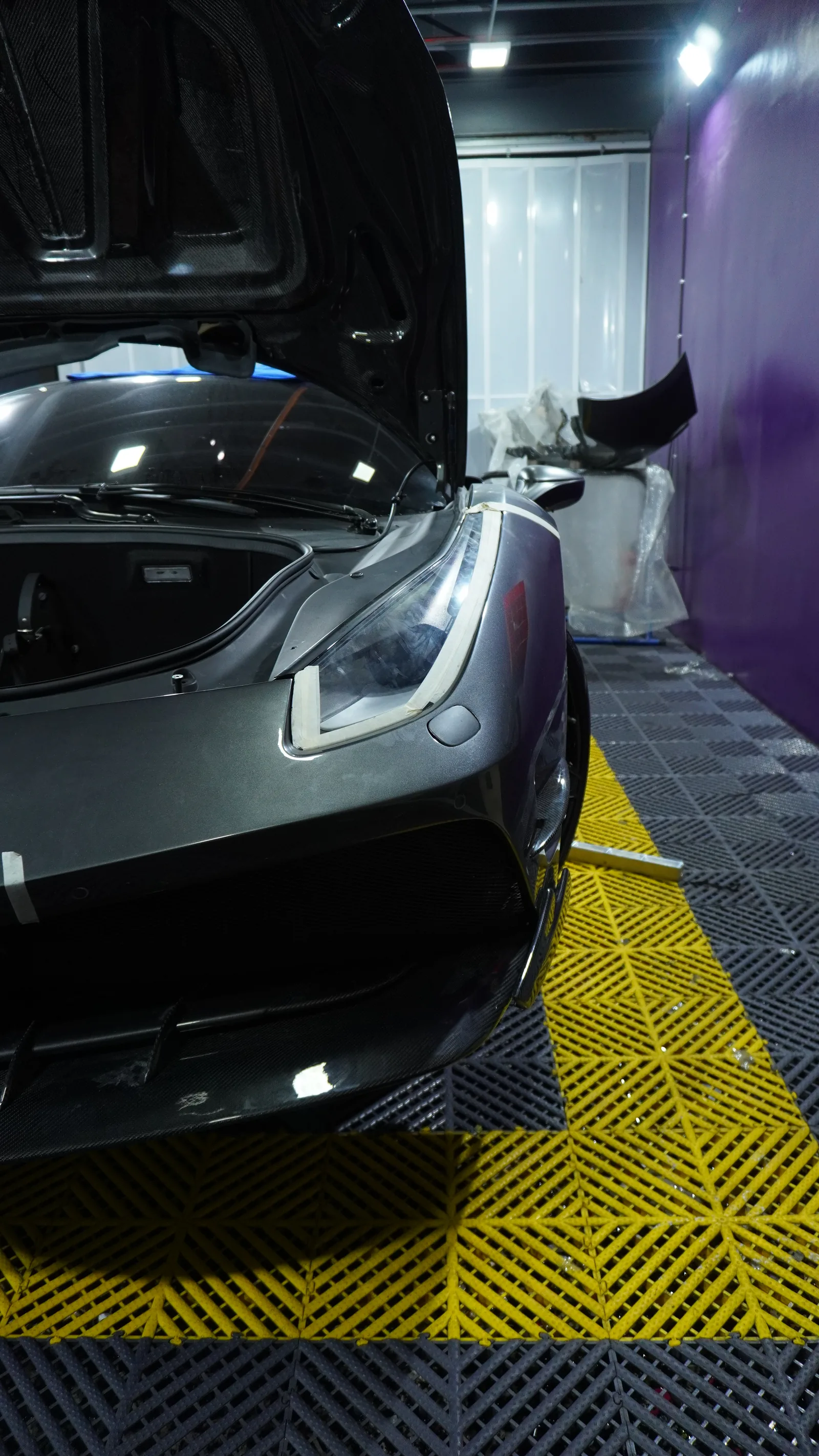 Ferrari 488 Spyder front end mid-fit, with the carbon bonnet raised and the headlight taped for protection