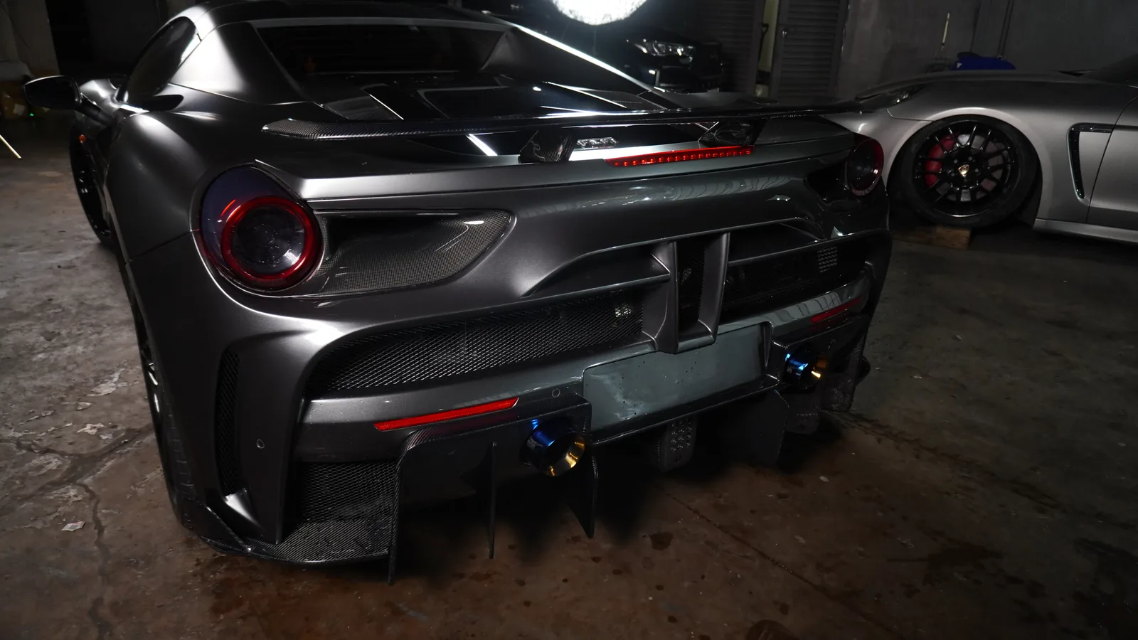 Rear three-quarter view of the matte grey Ferrari 488 Spyder showing the carbon diffuser and kit