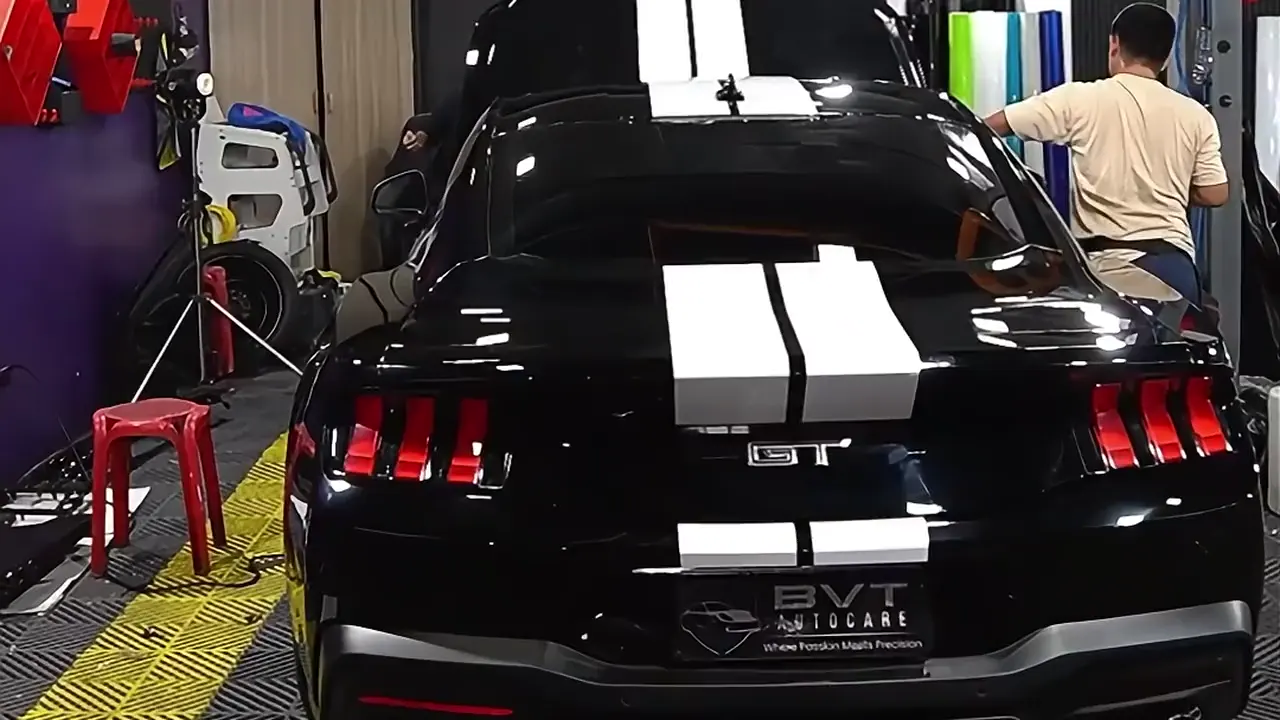 A black Ford Mustang with white stripes in the BVT Tuning PPF bay, the first shot of the workshop film