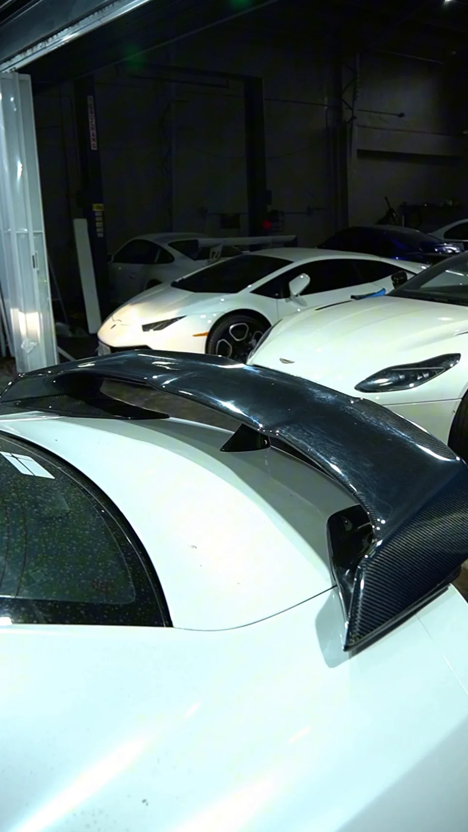 Carbon fibre rear wing on a white Nissan GT-R R35 with other cars parked behind