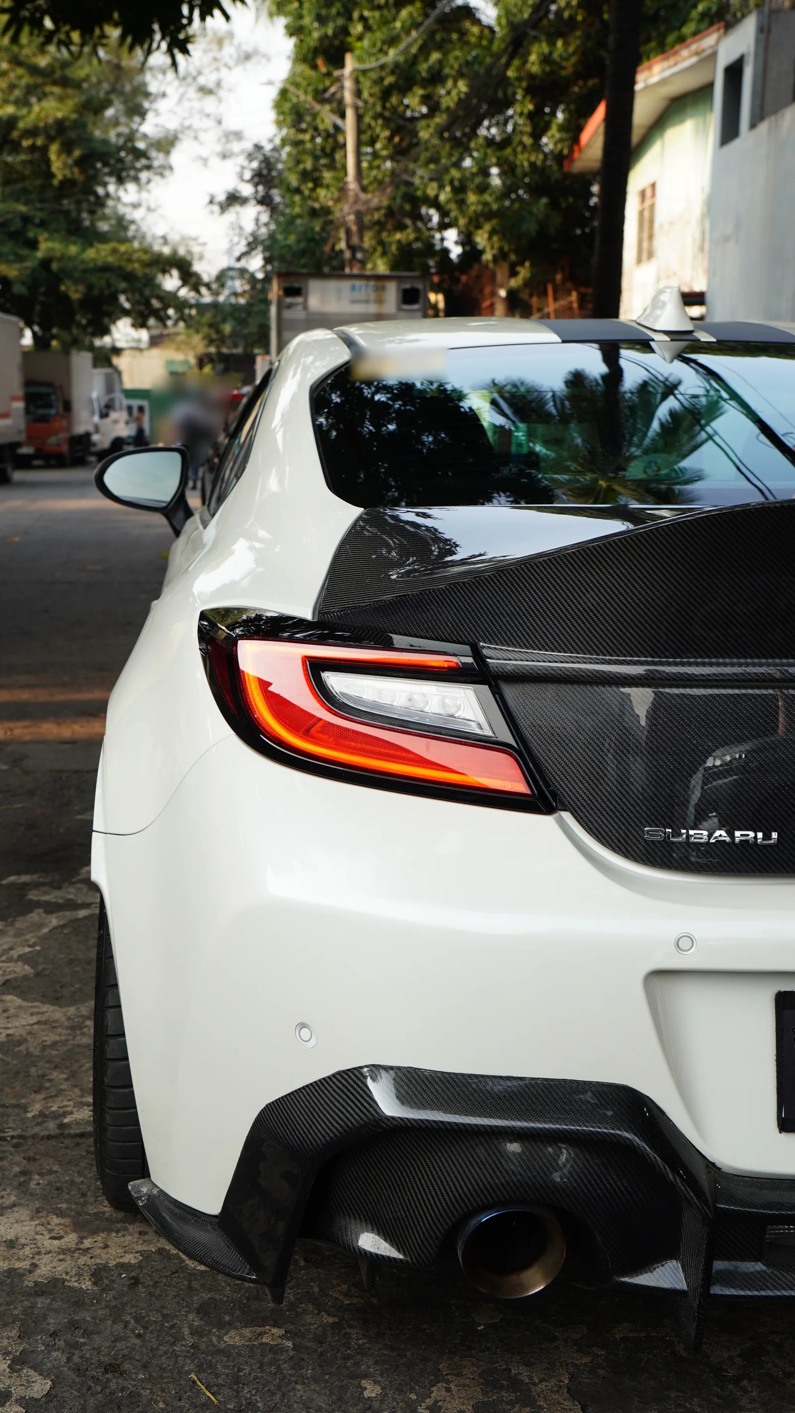 Rear three-quarter of a white Subaru BRZ with the carbon fibre trunk lid fitted