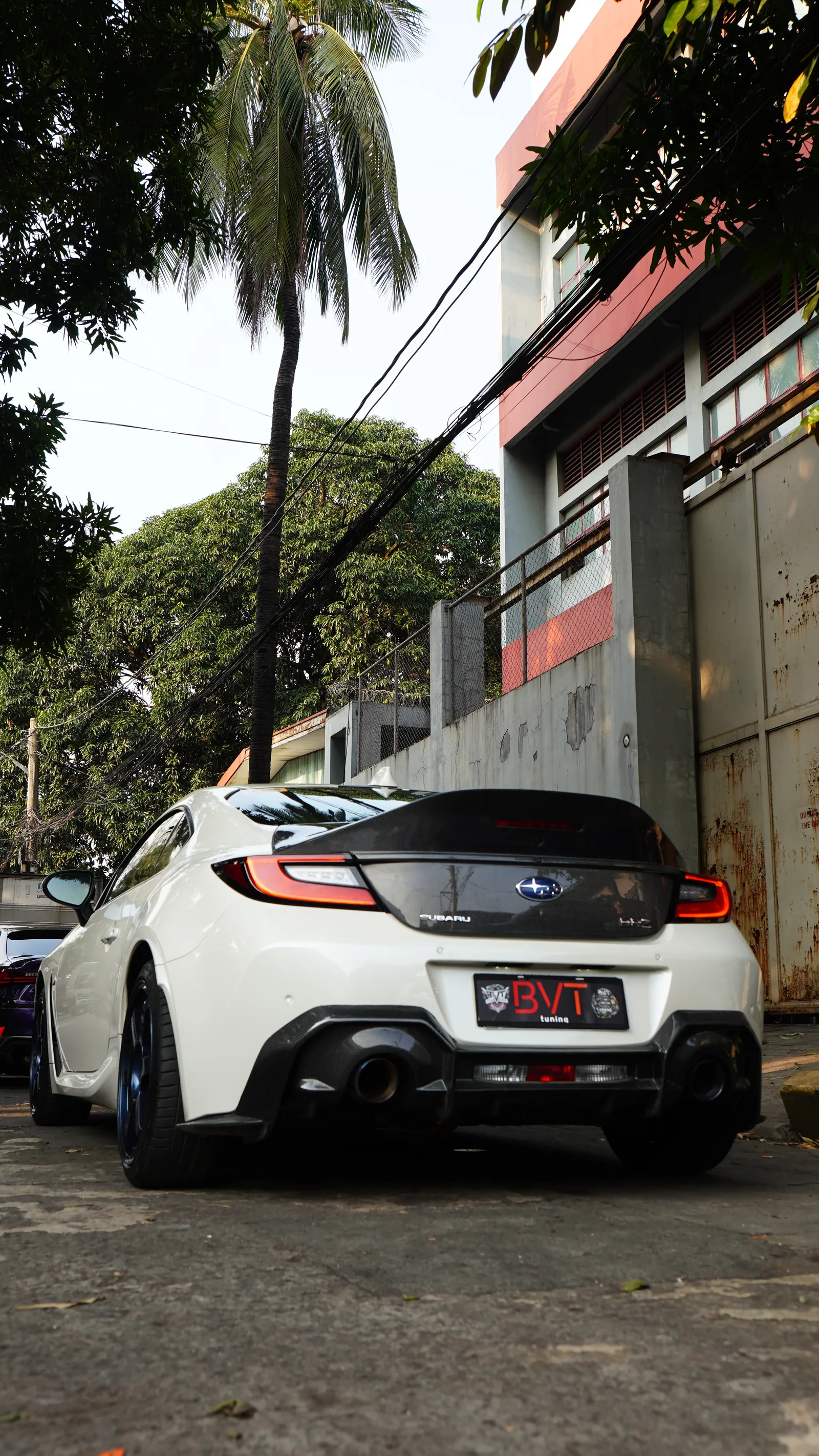 White Subaru BRZ from the rear with the carbon trunk lid and diffuser, parked outside the shop