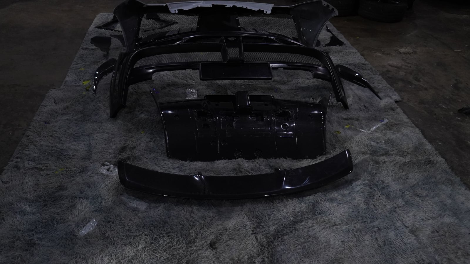 Ferrari 488 Spyder body-kit parts laid out on a rug on the BVT Tuning workshop floor before fitting