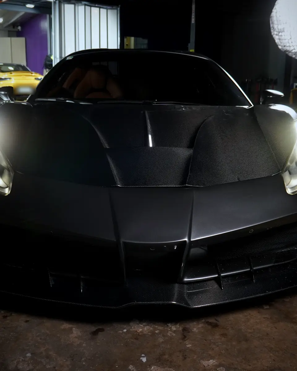 Ferrari 488 Spyder with a carbon body kit, headlights on, in the BVT Tuning workshop