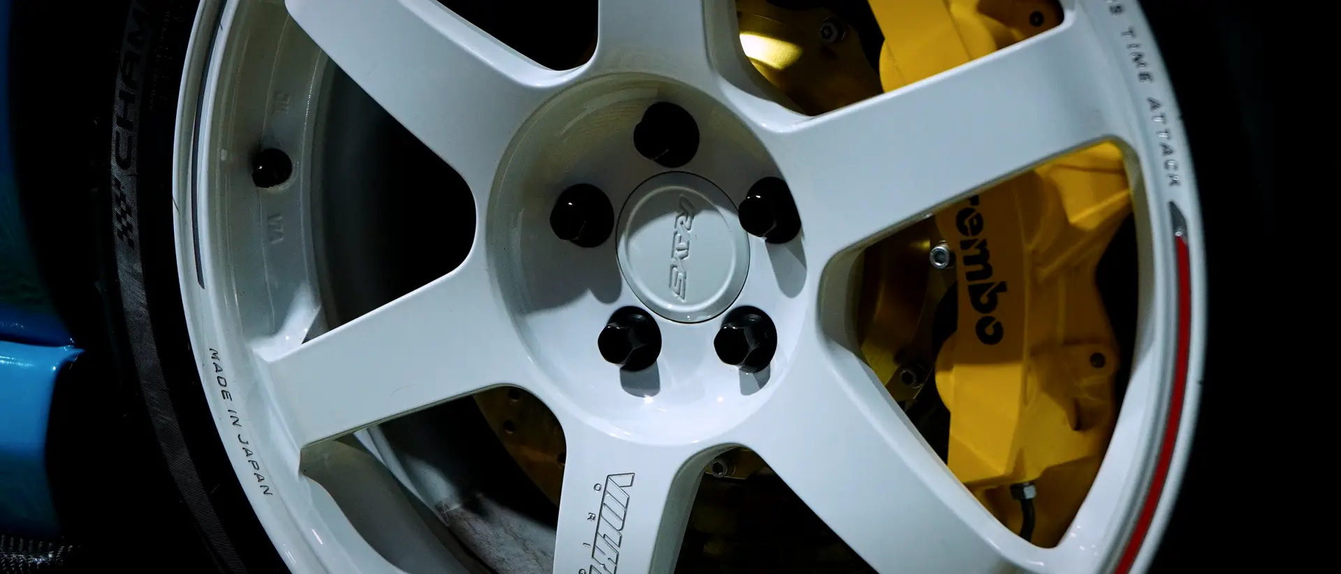 White forged wheel and performance tyre on a blue car in the BVT bay