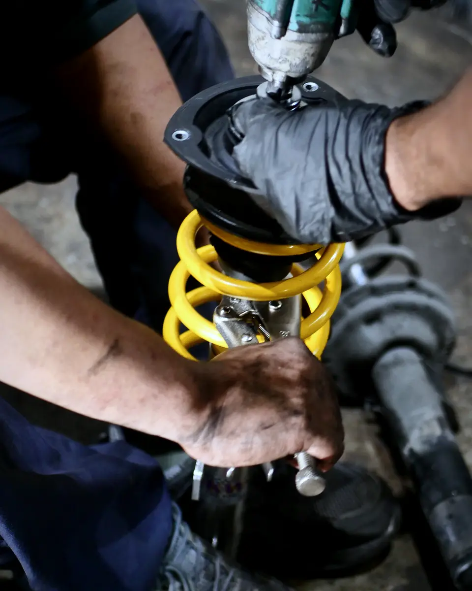 Hands fitting a coilover with an impact wrench