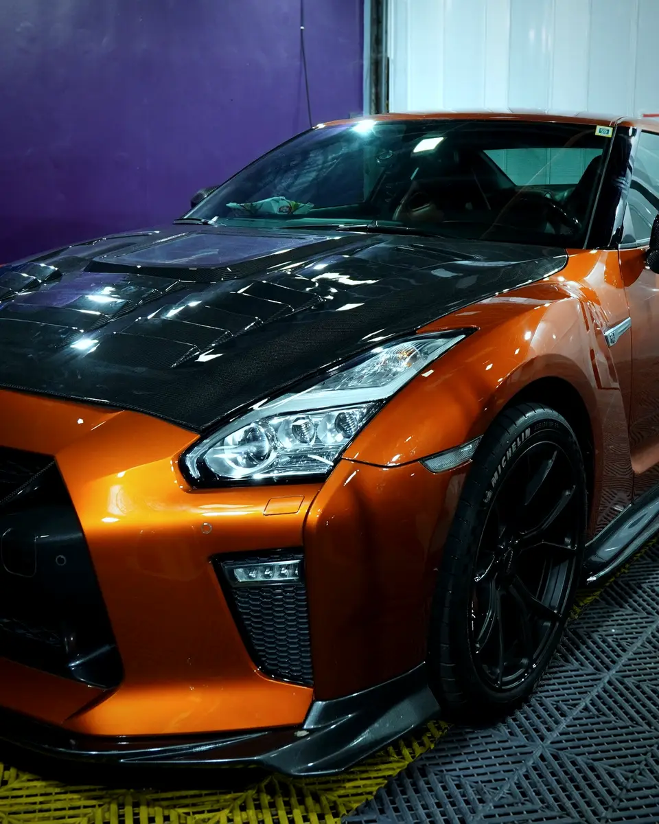 Orange Nissan GT-R with a carbon hood in the clean PPF bay