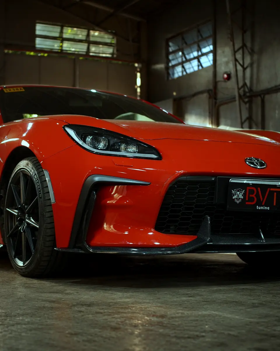 Red Toyota GR86 with carbon lip, skirts and wing in the clean BVT Tuning workshop