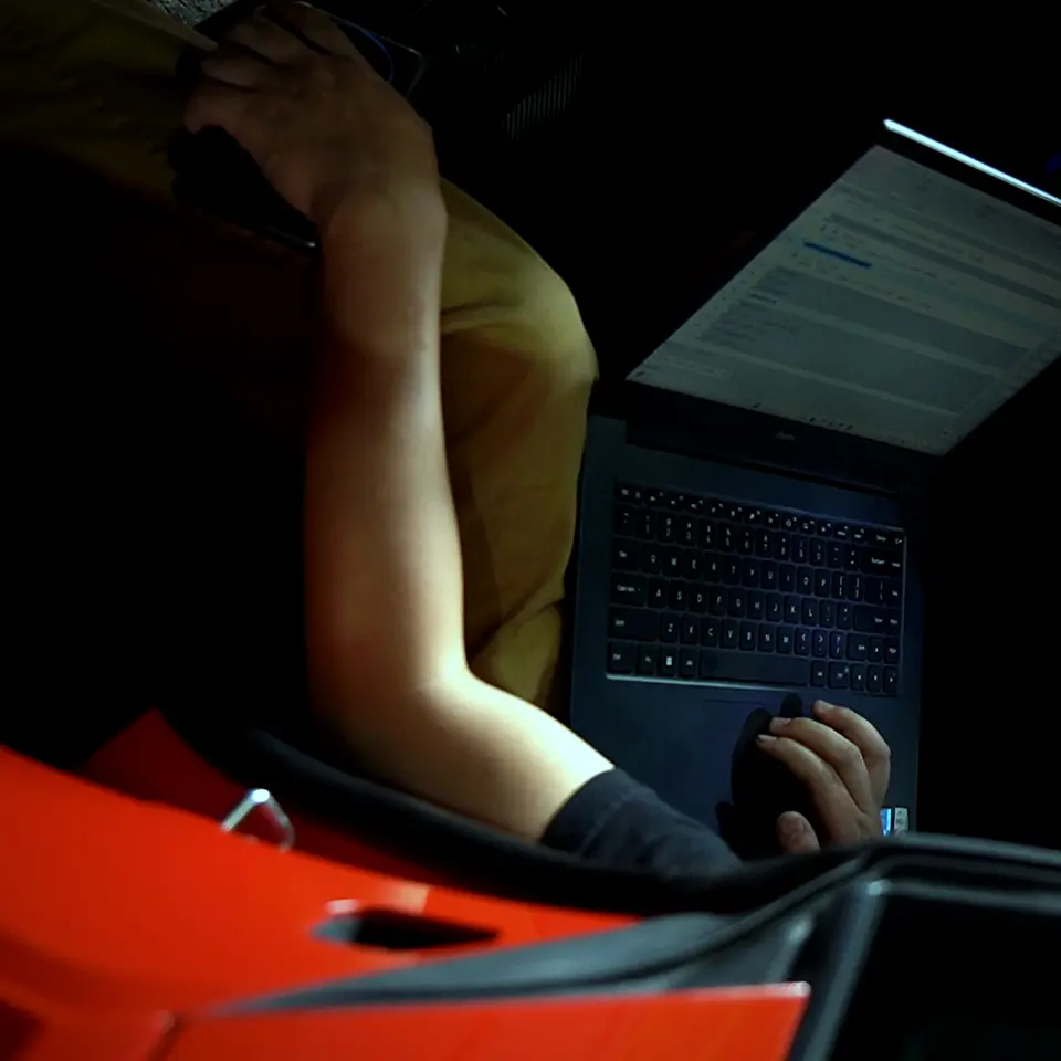 Laptop on a lap inside a Lamborghini Huracan, hands on the keyboard